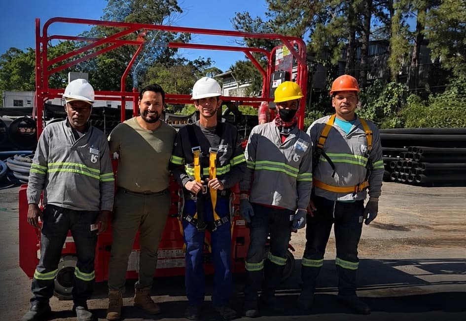 Equipe do Grupo Eleva Rental em frente a uma plataforma elevatória no pátio de operações